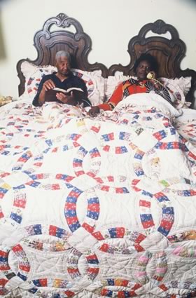 <b>Mr. and Mrs. Lucius and Mary Scarbrough in bed with her king-size Double Wedding Ring quilt, which she made to celebrate their fitieth wedding anniversary.</b>  Greene County, AL, April 1986.
